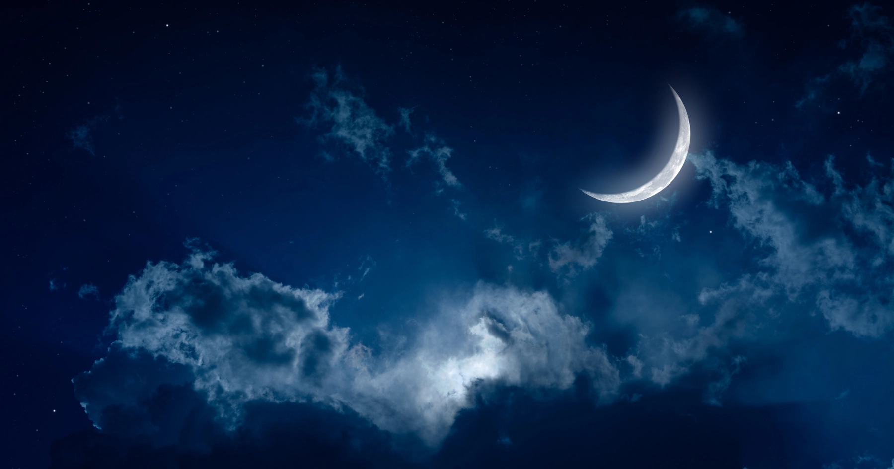 Mondsichel über Wolken am Nachthimmel – Sinnbild für das Träumen vom Zähneverlieren